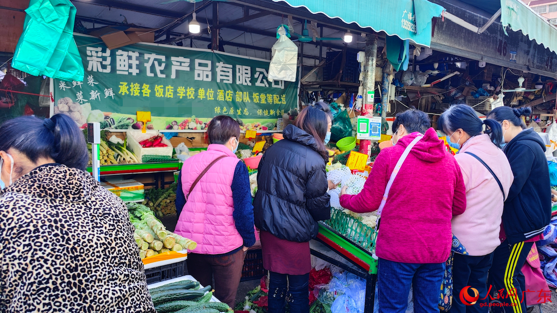 12月7日，在廣州市棠德農(nóng)副產(chǎn)品綜合市場，市民們圍在攤前，購買果蔬。樸馨語 攝